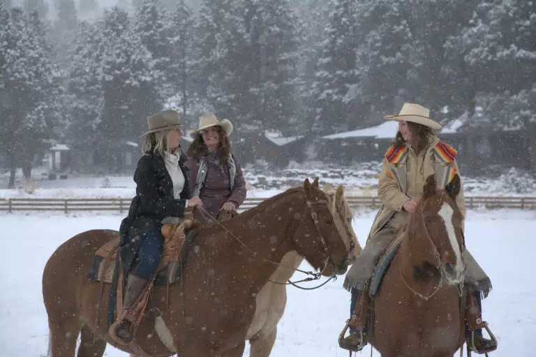 Cowgirls riding horses in the snow